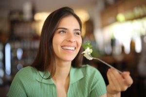 Woman eating vegetables and cheese after teeth whitening